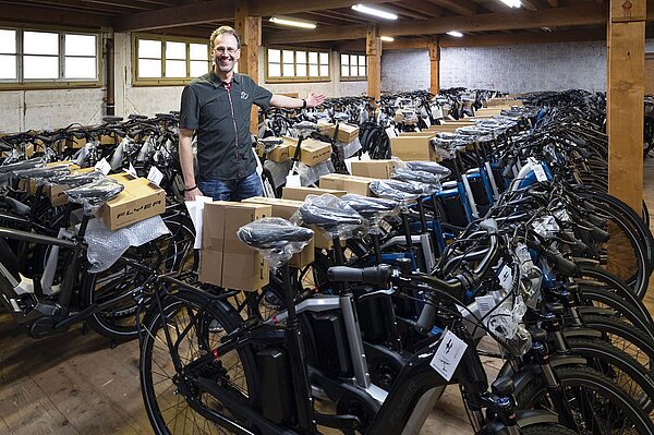 Ein Mann steht in einem Lagerraum, in dem viele Elektrovelos stehen