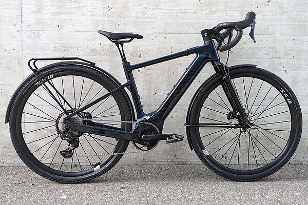 Canyon GrizlOn CF Daily im Test. E-Gravelbike mit Federgabel vor einer Betonmauer.