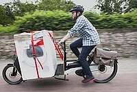 Mann transportiert Waschmaschine mit Lastenrad. Bonus für Cargobikes. 