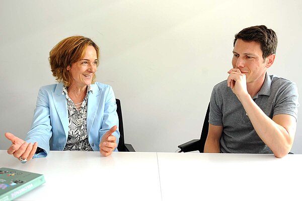 Zwei Personen sitzen an einem Tisch.