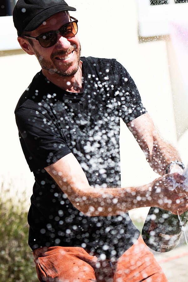 Ein Mann spritzt mit einer Sektflasche.