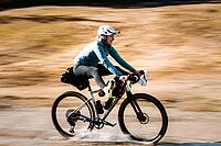 Eine Person fährt mit dem Gravelbike durch einen Bach.