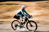 Eine Person fährt mit dem Gravelbike durch einen Bach.