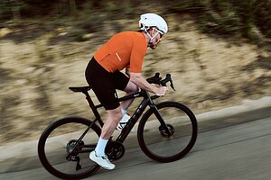 Rennradfahrer mit orangem Tricot auf E-Rennrad «Teammachine 01 AMP One» von BMC.»