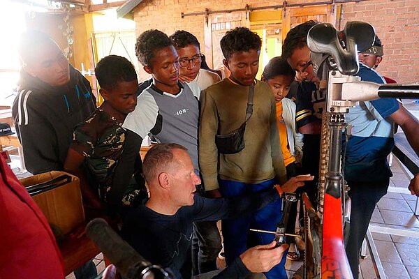 Ein Mann zeigt Jugendlichen wie an ein Fahrrad repariert.