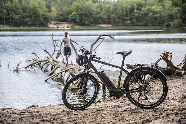 Ein Fahrrad steht an einem Seeufer. Im Hintergrund sind Bäume zu sehen