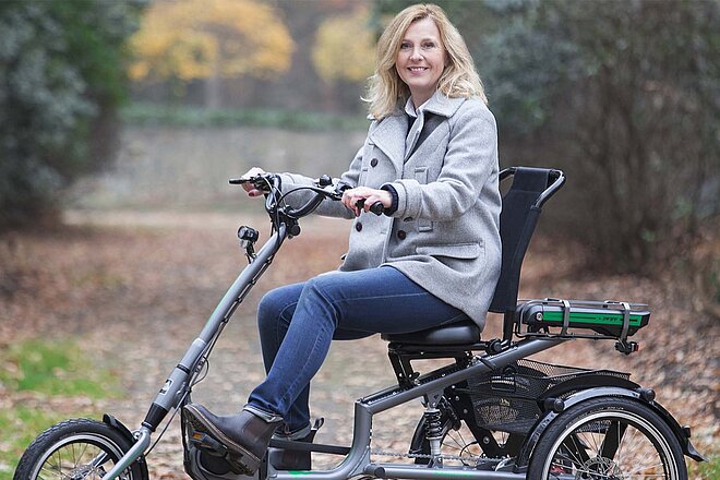 blonde Frau fährt auf Dreirad auf einem Waldweg