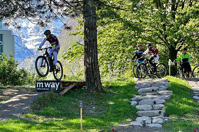 Bike-Skillspark Lintharena. Ein Mountainbiker fährt durch einen Bikepark.