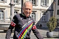 Ein Senior mit Fahrradtricot steht auf einem Platz.