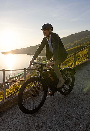 Motosacoche E-Bike. Ein Mann in Businesskleidung fährt auf einem E-Bike.