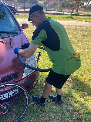 Rennradfahren in Korsika. Ein Mann im grünen Fahrradtricot flickt einen Schlauch.