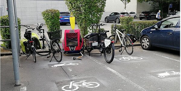hinter dem Coop Lenzburg stehen Cargobikes und ein Veloanhänger