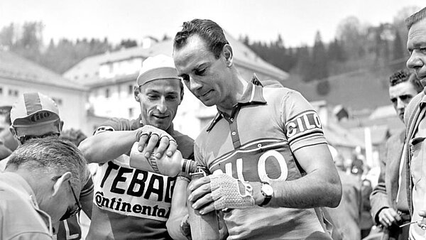 Fahrradproduktion in Europa. Zwei Radrennfahrer halten auf einem schwarzweiss Foto Getränke in den Händen.