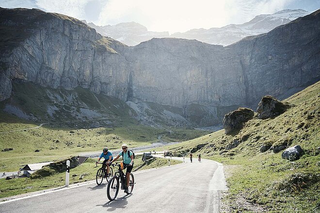 Am «Klausen Monument» am 11. September 2022 ist der Klausenpass für Autos gesperrt. Eine Frau und ein Mann mit Velo auf einer Strasse in den Bergen. 