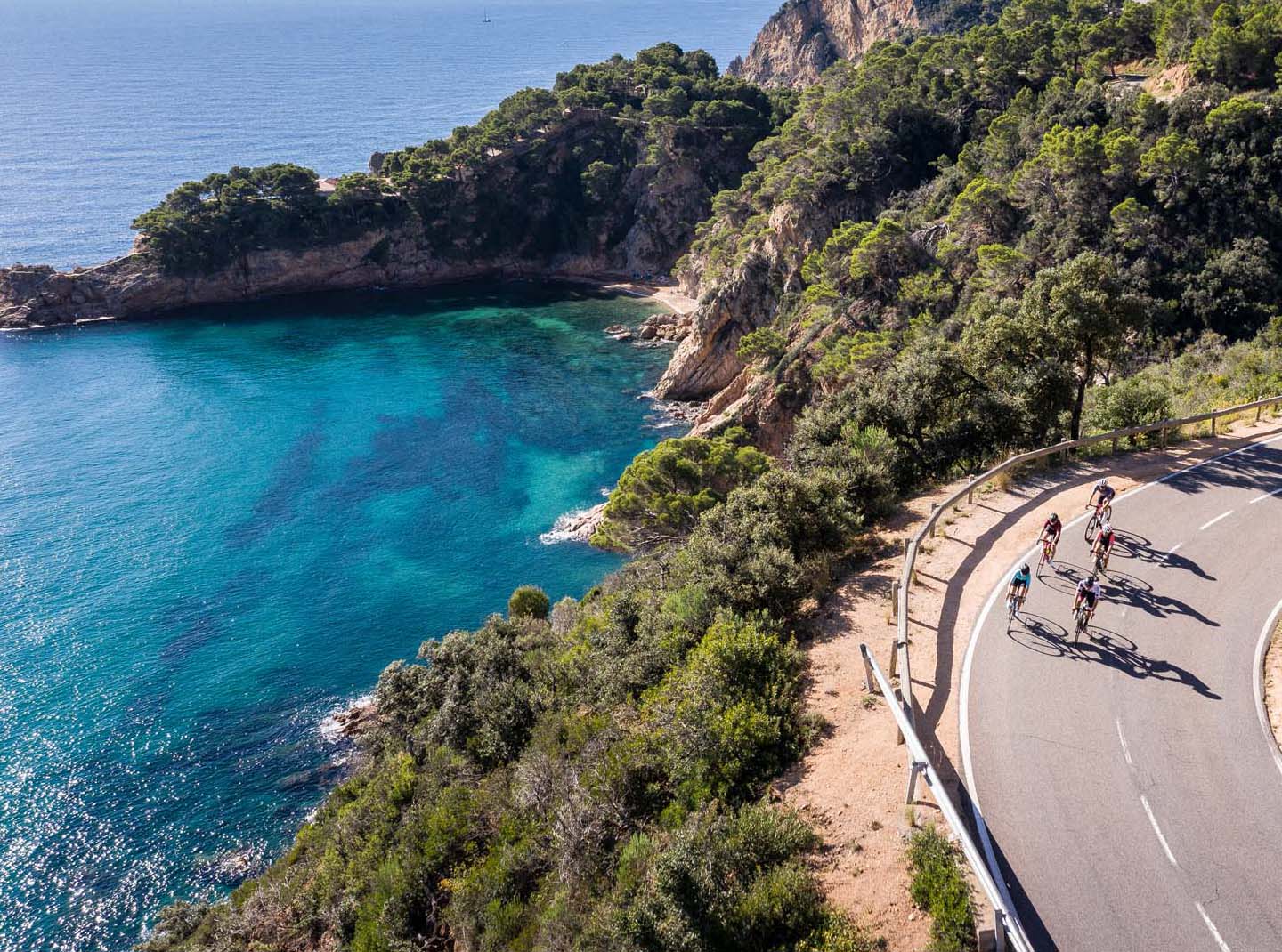 Rennradfahrer auf einer Küstenstrasse am Meer.